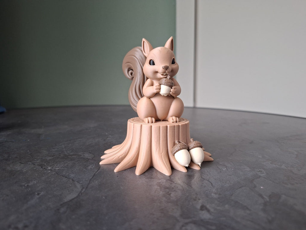 Niedliches Eichhörnchen das eine Eichel auf einem Baumstamm hält Figur Deko