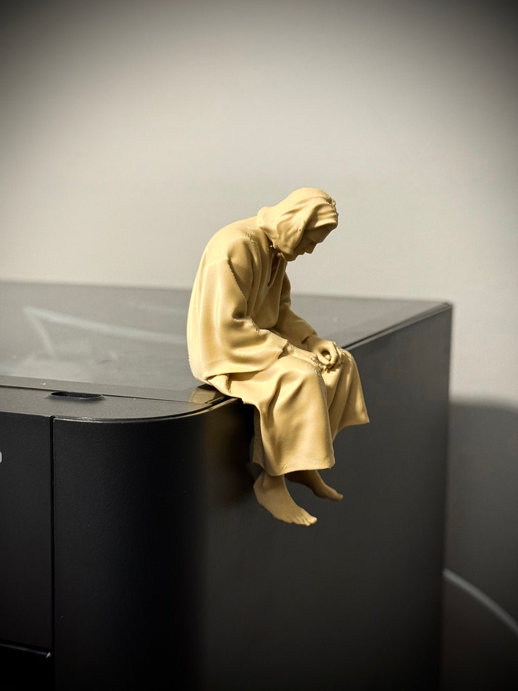 Figur Jesus traurig auf Kante sitzend